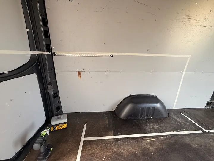 Tape on the wall and floor: the plan drawn out at full size in the van itself.