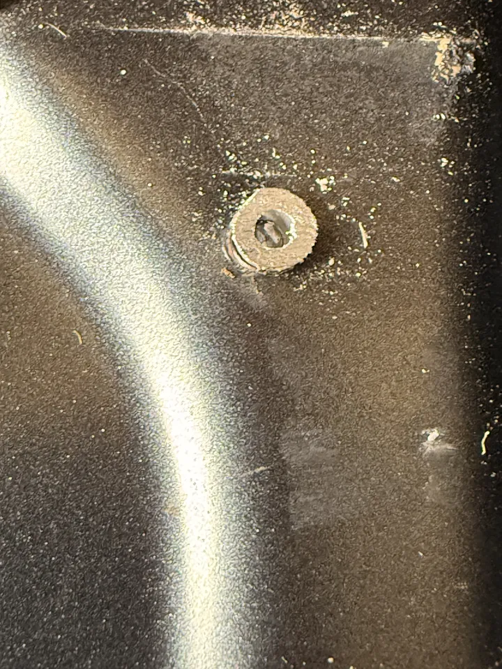A fastener ground down nearly flush with the panel.