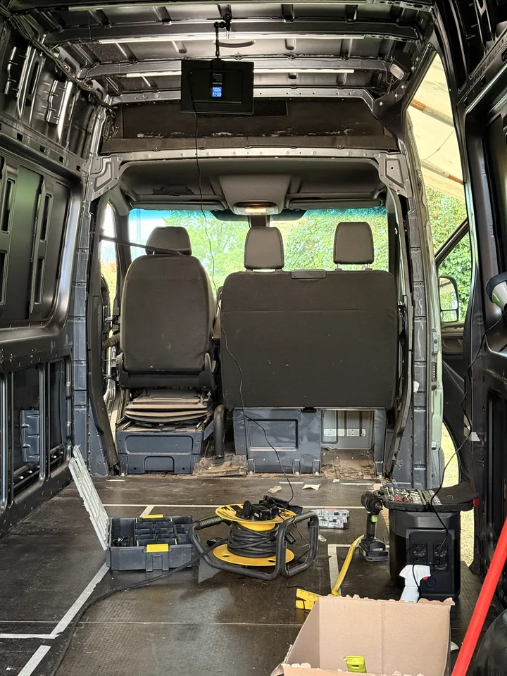 The cab from the cargo side. Seat bases exposed, bit set open, impact driver within reach.