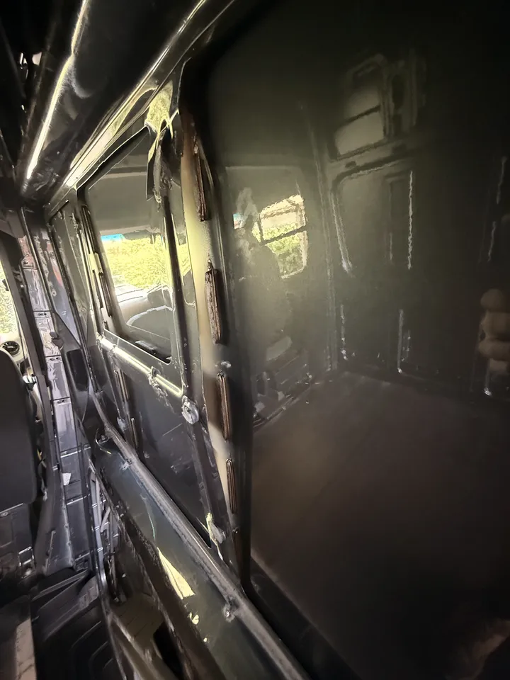 The front corner behind the driver seat, pillar and wall stripped, sealant traces where the trim sat.