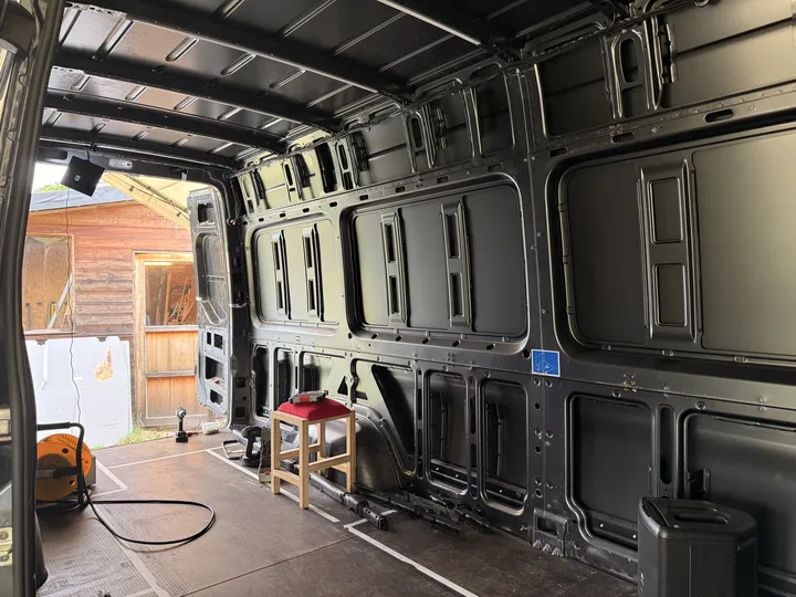 The load area stripped to bare metal, work light on the wall and removed parts on the floor